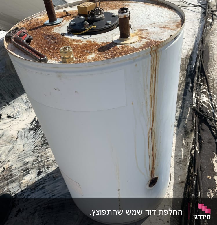 דוד שמש עם חלודה על הגג, צינורות וחיבורים גלויים